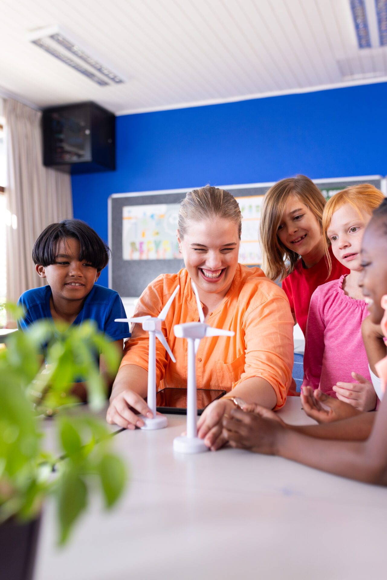 In school, female teacher and diverse students experimenting with wind turbine models in classroom. Education, science, engineering, renewable energy, STEM, learning